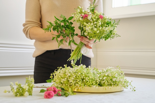 Frauenflorist mit verschiedenen Blumen auf dem Tisch, der Blumenstrauß macht