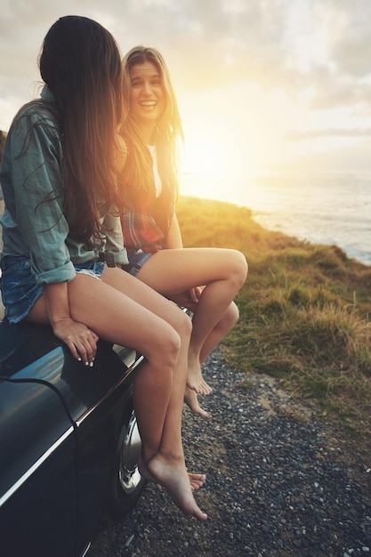 Frauenfreunde Roadtrip und Sonnenuntergang in der Natur für Reiseabenteuer und Freiheit, während sie glücklich im Freien sind Lustige Mädchen auf einem Auto, während sie im Urlaub fahren oder reisen mit Transport und Meerblick