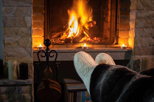 Frauenfüße am Kamin, der bequem von zu Hause aus beleuchtet wird.