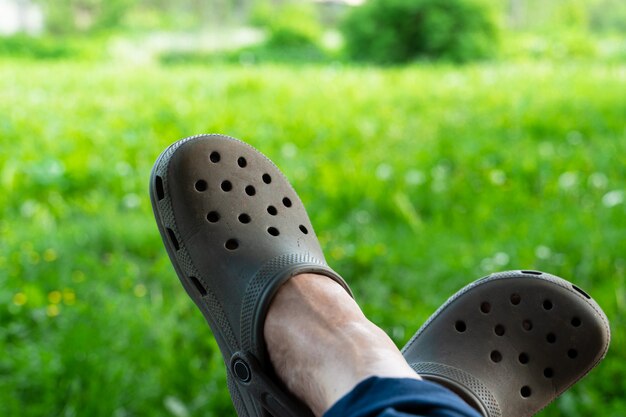 Frauenfüße in Gartenschuhen auf grünem Rasen