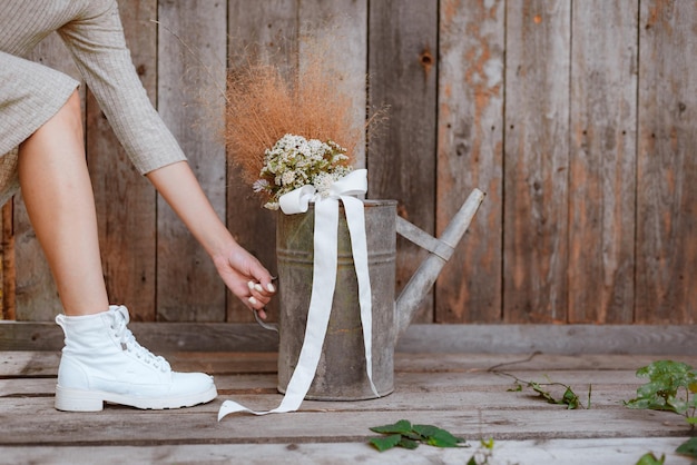 Frauenfüße in Kleid und weißen Schuhen Mode Hintergrund Holzbohlen Gärtner Eisen Gießkanne fre