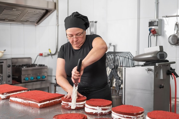 Frauengebäckchef, der glücklich lächelt und arbeitet und Kuchen an der Konditorei macht.