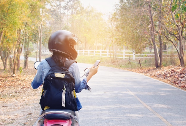 Frauengebrauchstelefon und -motorrad im Straßenrand.