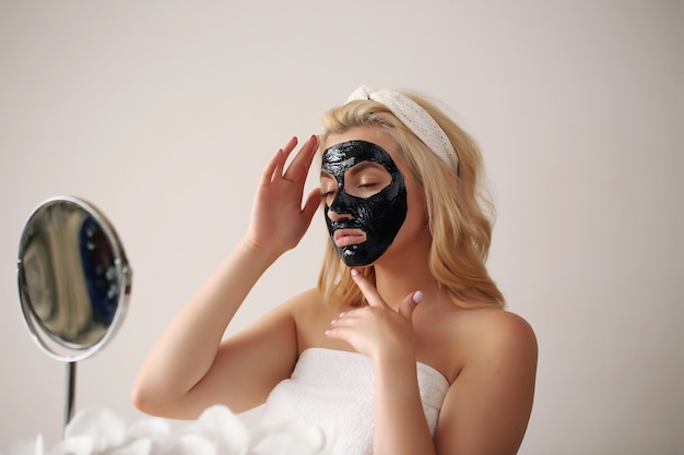 Frauengesicht mit schwarzer Peeling-Maske auf der Haut. Anwenden der kosmetischen Maske auf Gesicht.