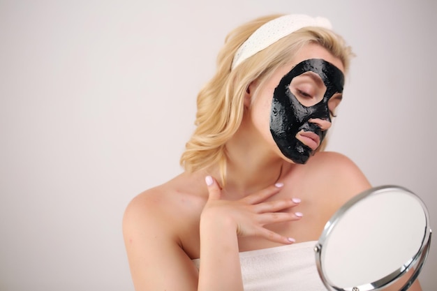 Foto frauengesicht mit schwarzer peeling-maske auf der haut, auftragen einer kosmetischen maske auf das gesicht