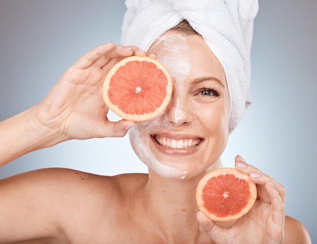 Frauengesichtsmaske oder Grapefruit-Hautpflege auf Studiohintergrund in Kanada Healthcare Wellness Bio-Dermatologie oder vegane Gesichtsbehandlung Porträtlächeln oder glückliches Schönheitsmodell mit Zitrusfrucht-Gesichtsprodukt