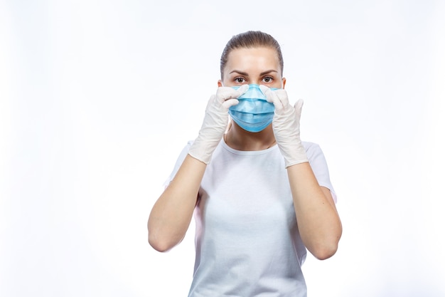 Frauengesundheitsarbeiterin zeigt, wie man eine medizinische chirurgische Schutzmaske gegen das Virus trägt. Isoliert auf weißem Hintergrund
