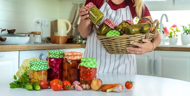 Frauenglaskonservengemüse in der Küche Selektiver Fokus