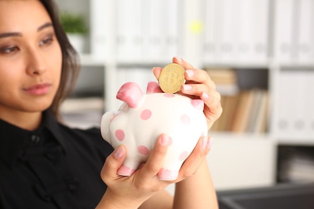 Frauengriffsparschwein in den Armen steckte Geld in moneybox