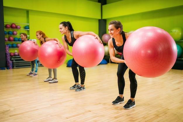 Frauengruppe mit großen bällen, die übung, fitness tun