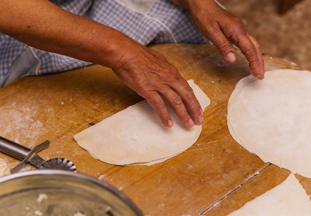 Frauenhände beim Kochen von Kutaba oder Chebureks Hackfleisch und Zwiebeln im TeigHüttenkäse und Zwiebeln im Teig Aserbaidschanische tatarische kaukasische griechische Küche