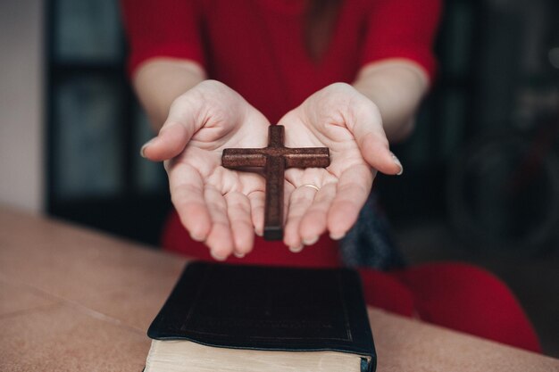 Frauenhände beten mit Holzkreuz zu Gott