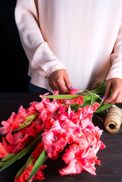 Frauenhände bilden einen Blumenstrauß aus Gladiolen