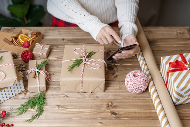 Frauenhände, die Bilder des Weihnachtsgeschenks am Telefon machen.