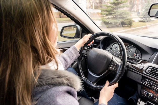 Frauenhände, die das Lenkrad eines Autos halten