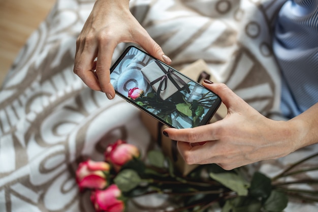 Frauenhände, die ein Mobiltelefon halten und Fotos von Blumen machen