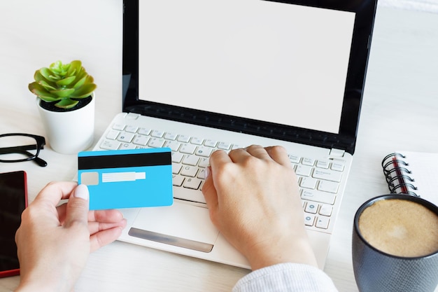 Frauenhände, die eine Kreditkarte halten und Computer für Online-Einkäufe verwenden