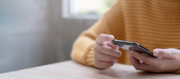 Frauenhände, die eine Kreditkarte halten und das Smartphone für Online-Shopping verwenden