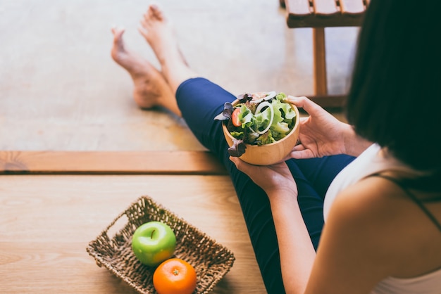 Frauenhände, die gesunden Salat für Frühstück am Morgen halten und essen