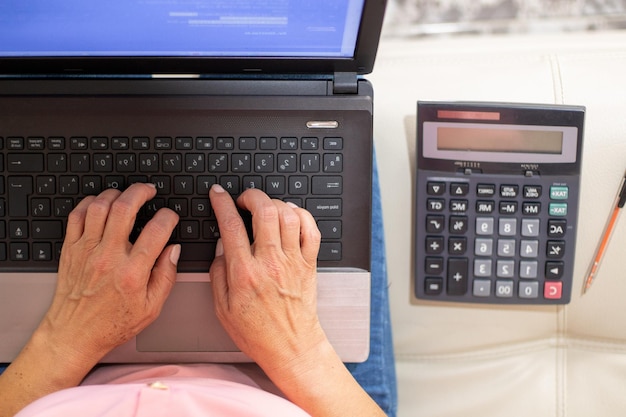 Frauenhände, die im Finanzbereich arbeiten und mit ihrem Laptop und Taschenrechner arbeiten