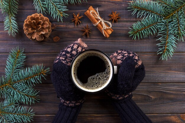 Frauenhände, die Kaffeetasse, mit mit Weihnachtsbaumasten, Kiefernkegel, auf Marmortabelle, Draufsicht halten