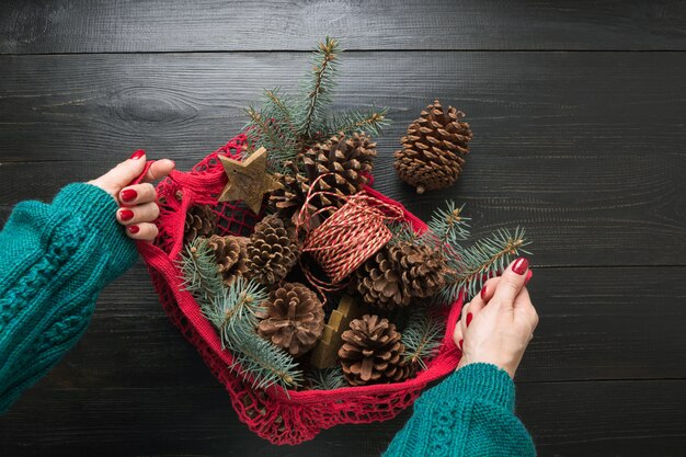 Foto frauenhände, die maschentasche mit weihnachtsnullabfalldekor, natürlichen kegeln für handgemachte geschenke und diy halten.