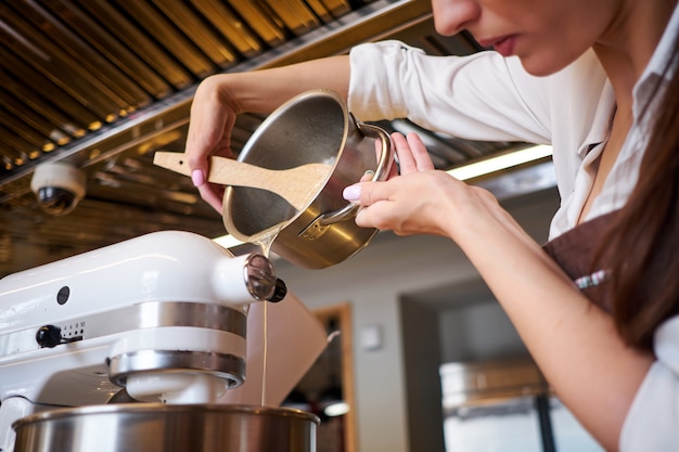 Frauenhände, die mit Mischer peitschen. Dessert in moderner Küche zubereiten