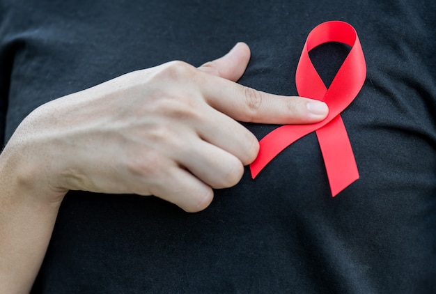 Frauenhände, die rotes AIDS-Bewusstseinsband halten