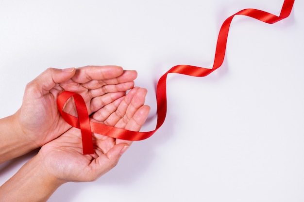 Frauenhände, die rotes Band, HIV-Bewusstseinskonzept oder Welt-AIDS-Tageskonzept halten