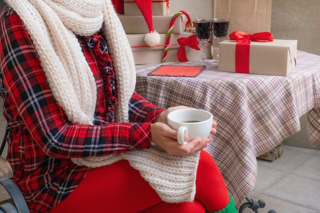 Frauenhände, die Tassen Tee oder Kaffee halten, gekleidet in rote und weiße festliche Kleidung.