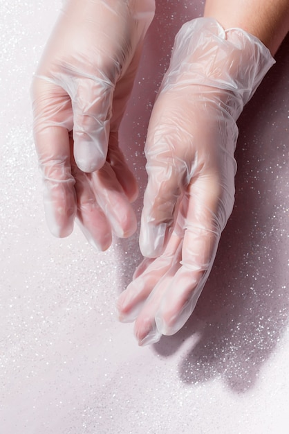 Frauenhände, die transparenten Einwegplastikhandschuh auf Weiß tragen