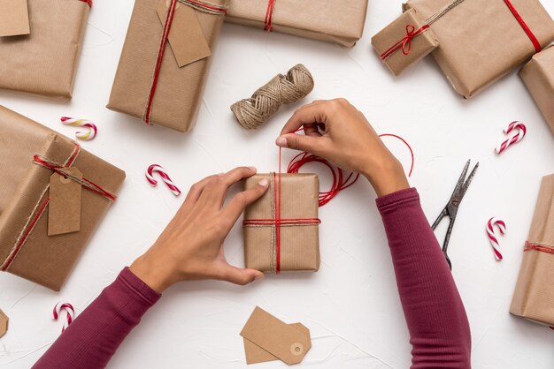 Frauenhände, die Weihnachtsgeschenkboxen einwickeln