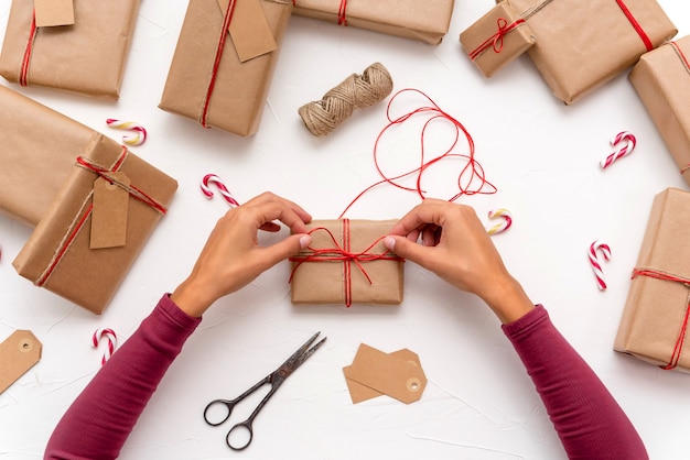 Foto frauenhände, die weihnachtsgeschenkboxen einwickeln