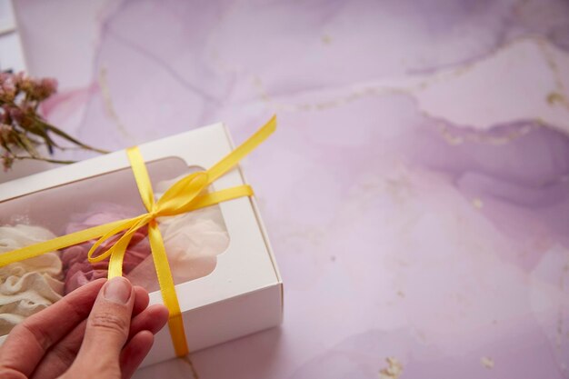 Frauenhände geben eine Geschenkbox mit rosa und weißem Marshmallow aus nächster Nähe Boxing Day Konzept Gemütliche Winterwochenenden Hausgemachte Süßigkeiten Kopieren Sie Platz