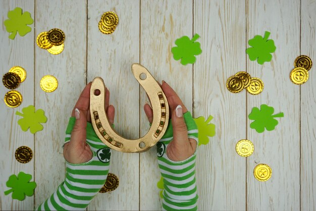 Frauenhände halten am St. Patrick's Day ein goldenes Hufeisen