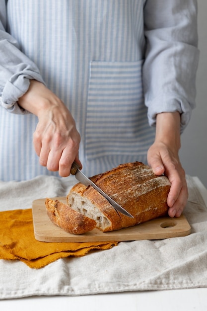 Frauenhände halten Brot vor dem Hintergrund einer leichten Schürze