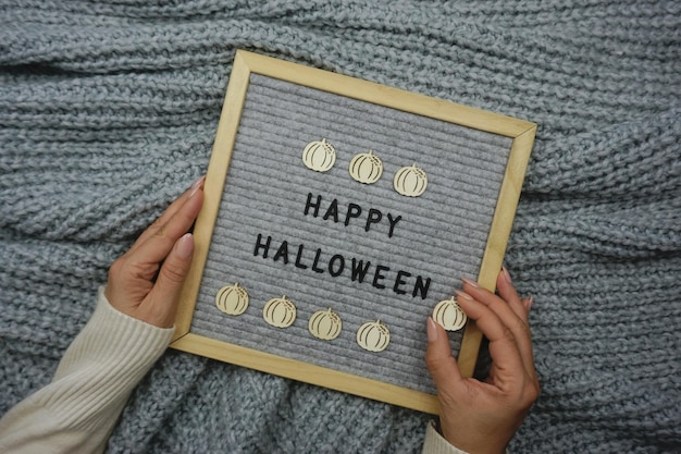 Frauenhände halten ein Brett mit dem Text - Happy Halloween