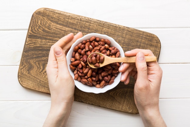 Frauenhände halten eine Holzschale mit Erdnüssen. Gesundes Essen und Snack. Vegetarische Snacks aus verschiedenen Nüssen