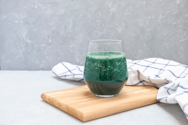 Frauenhände halten Tasse natürlichen Entgiftungsspirulina-Smoothie