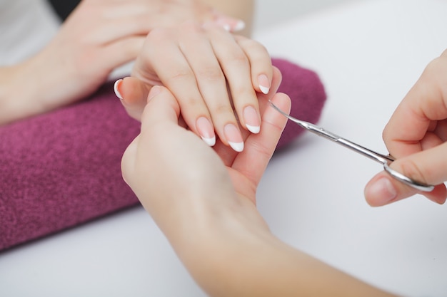 Frauenhände in einem Nagelsalon, der ein Maniküreverfahren empfängt