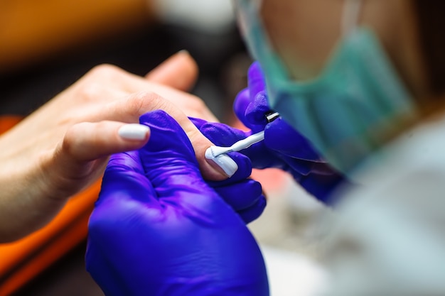 Frauenhände in einem Nagelsalon, der eine Maniküre empfängt. Close up, Tiefenschärfe.