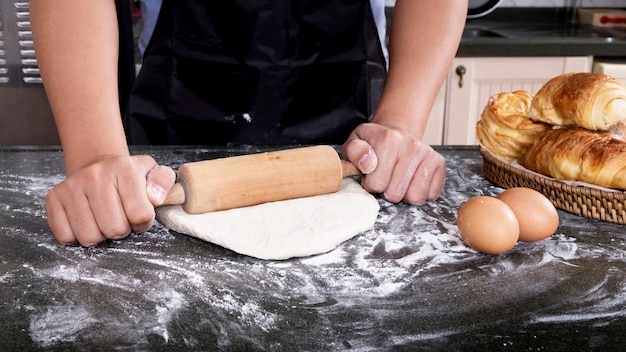 Frauenhände kneten Teig mit Mehl, Eiern und Bestandteilen an der Küche