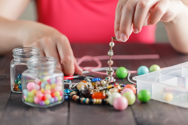 Frauenhände machen Armband mit Plastikperlen