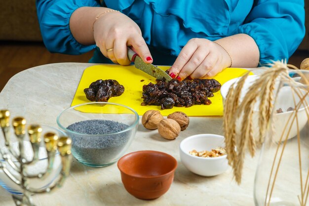 Foto frauenhände machen pflaumenfüllung für mohn-gomentashi-kekse, die traditionell für die juden sind