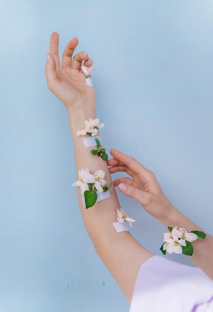 Frauenhände mit Frühlingsblumen auf blauem Hintergrund künstlerische Weiblichkeit Blumenhintergrund Verbindung mit natureFlowers mit Klebeband verklebt Women's Health Skin Care Cosmetics