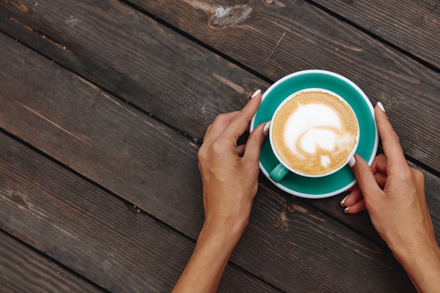 Frauenhände mit heißer Kaffeetasse mit schöner herzförmiger Latte Art