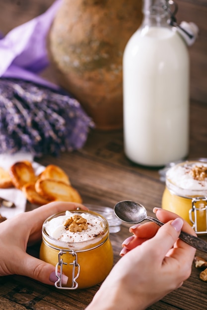 Frauenhände mit Löffel. Kürbismilchshake im Glas mit Schlagsahne, Toffee, Walnuss und Honiggebäck