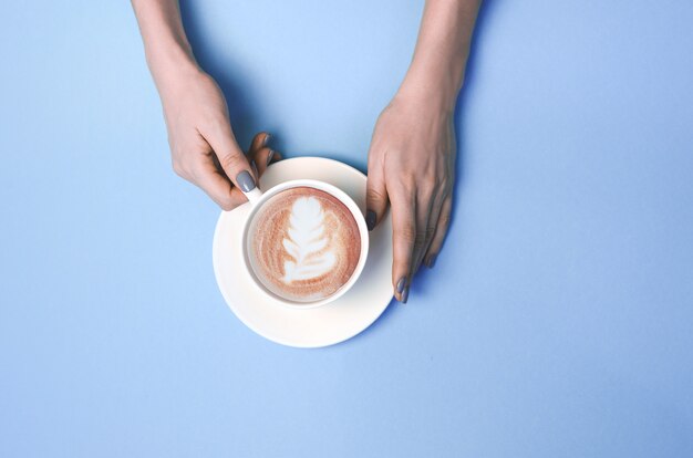 Frauenhände mit Tasse Kaffee mit Latte Art