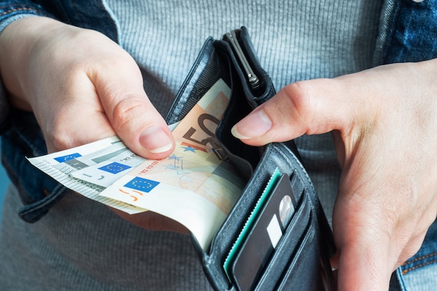 Frauenhände nehmen Geld Euro aus ihren Brieftaschen.