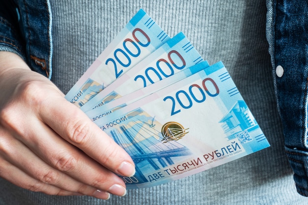 Frauenhände nehmen Geld Rubel aus ihren Brieftaschen.
